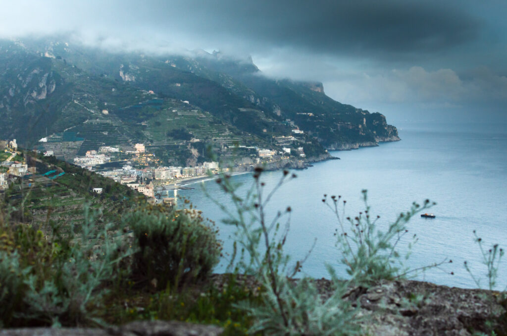 The panorama of Maiori and the coastline in a rainy day, Amalfi Coast, Italy. Green hills and mountains at dusk, the sea shore with greyish clouds.