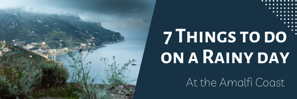Image with text reading "7 things to do on a rainy day" overlaid on a photo of the coastline of the Amalfi Coast in Italy. The image depicts green hills and mountains at dusk, and the sea shore with greyish clouds suggesting a rainy day. The panoramic view of the coastline and sea creates a peaceful and serene atmosphere