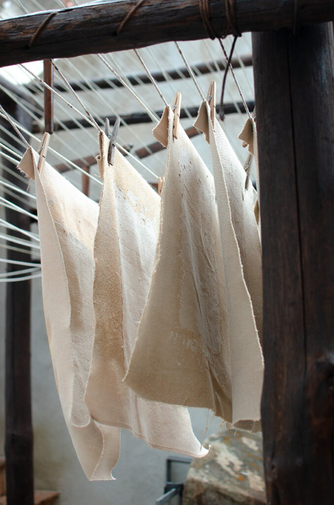 A photo of several sheets of handmade paper hanging from a clothesline. 