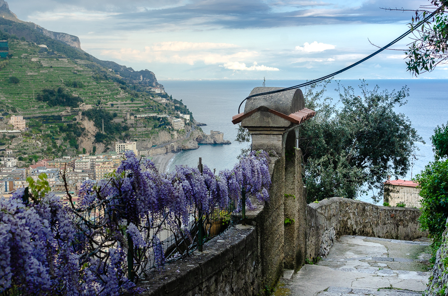 Captivating sea view from the Lemon Path, showcasing the picturesque trail adorned with hanging purple flowers on an old stone gate, offering a delightful journey along the Amalfi Coast