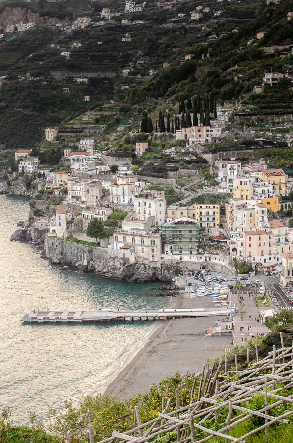 Scenic view of Minori Bay at sunset golden hour, showcasing the tranquil beauty of the bay, the shimmering sea, and the charming coastal town nestled along the Amalfi Coast. Lemon terraces in the foreground of image.