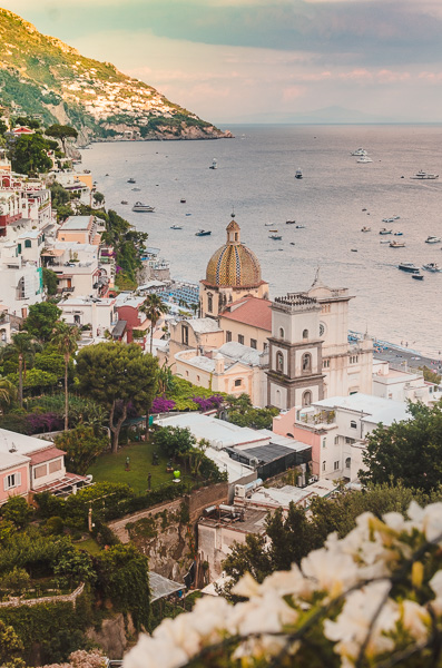 Positano, the view of the seaside and the church, one off the most famous town on the Amalfi Coast, Italy. Pastel coloured image, with white bucanville flower on the front.