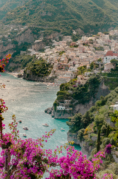 Positano from further away. View with purple flowers in the front.