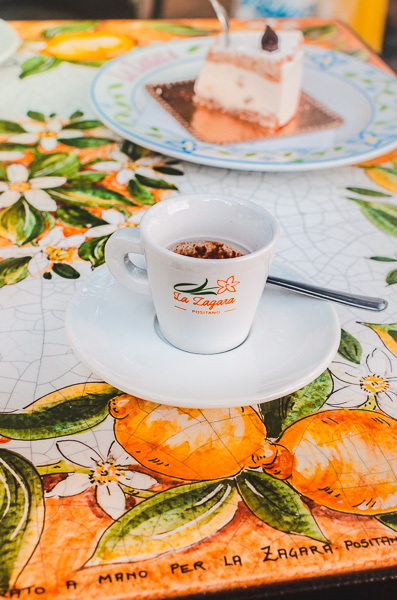 Zagara, a famous patisserie in Positano, showcasing a café scene with a ceramic table top adorned with hand-painted lemons and lemon flowers.