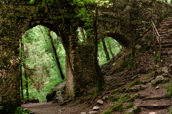 Ferriere Valley, The two monumental arches made of stones. The Ruins are on the path of the Valle delle Ferriere, inside the lush green forest. The trail continuous under the big arch.