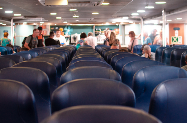 People boarding the ferry to Capri.
Dark blue seats on the foreground. 
