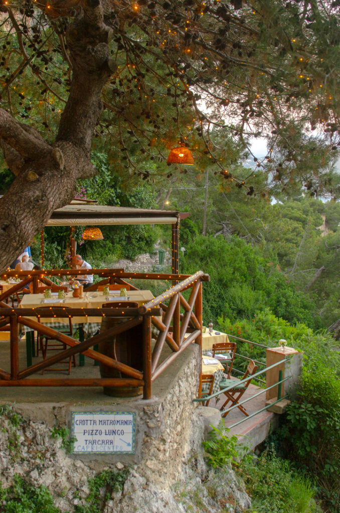 Restaurant terrace in Capri. Wooden fences, with little ambient lights under a pine tree.