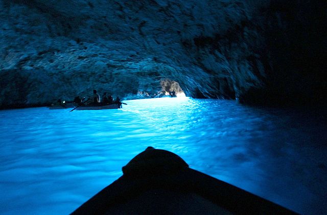 Glowing blue water inside the dark cavern of the Blue Grotto, a natural wonder of Capri.