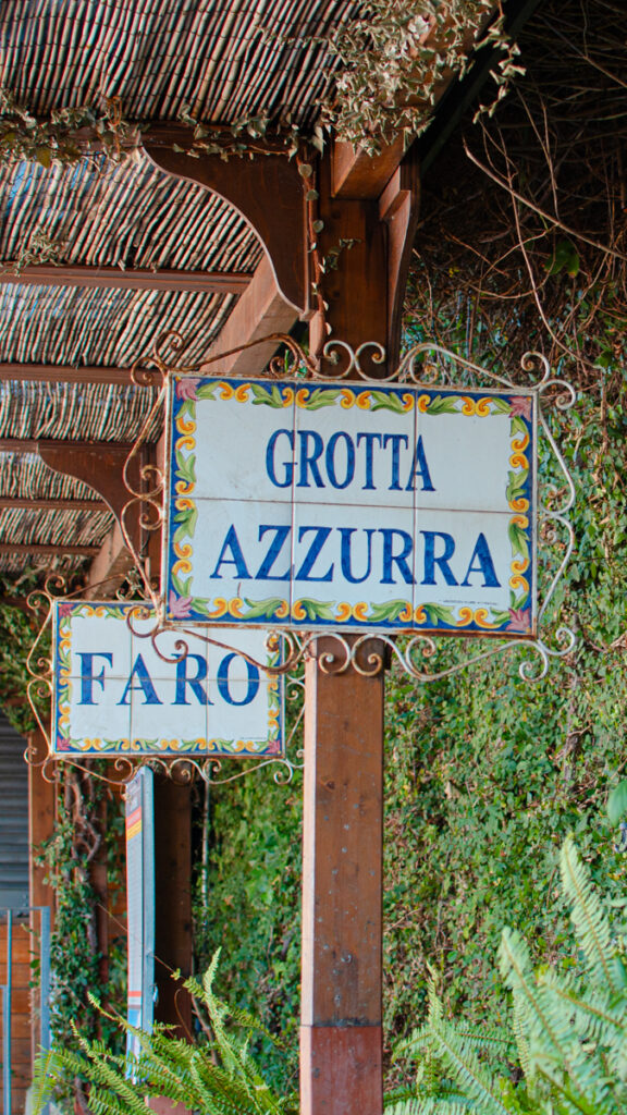 Hand-painted ceramic signs adorned with intricate designs indicating the departure points for Grotta Azzurra (Blue Grotto) and Faro (Lighthouse) in Anacapri.