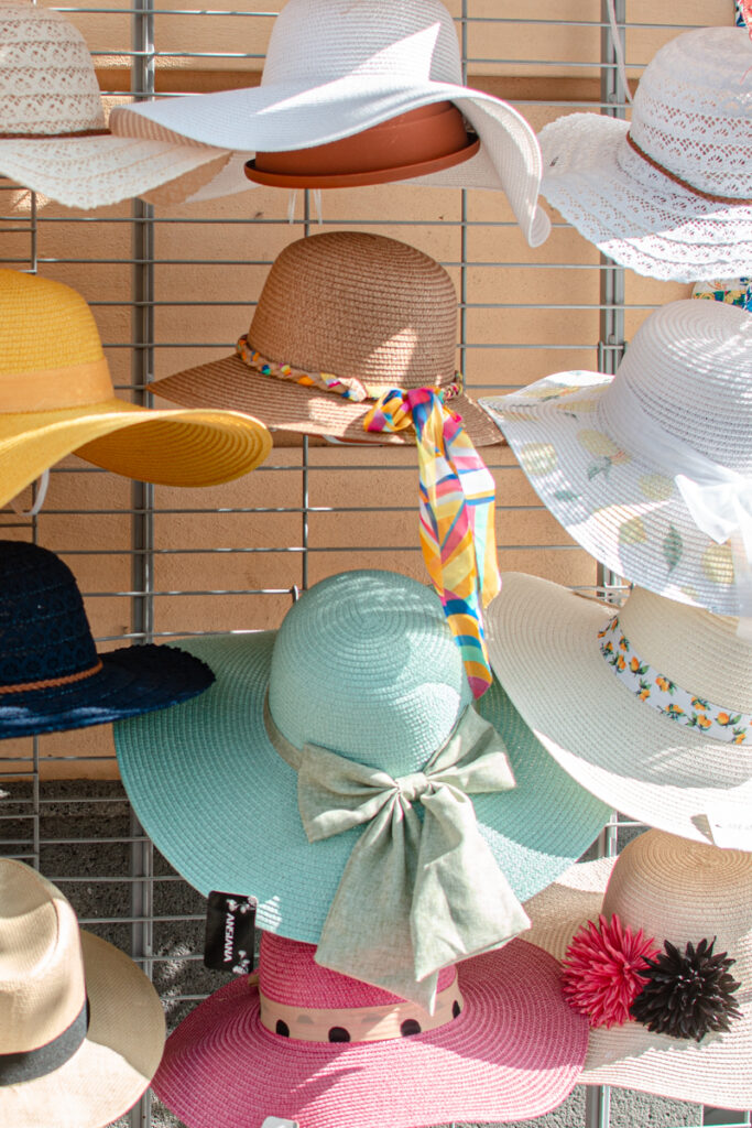 Straw sun hats on display at the shop entrance, mint-colored with a huge bow in the middle.