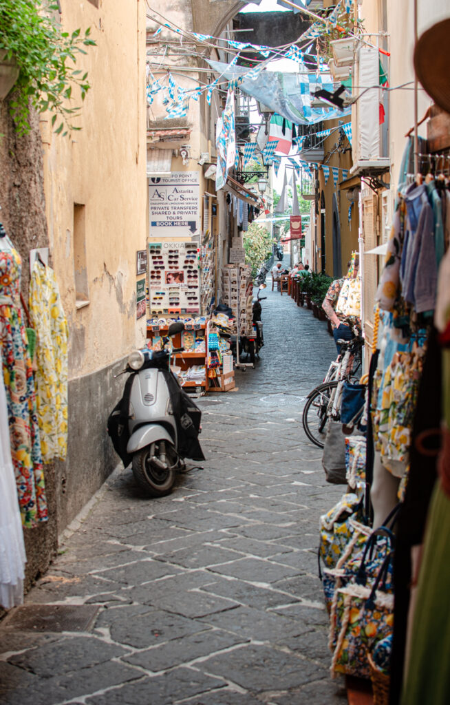 Little alleyway in Sorrento, lined with souvenir shops and a motorbike parked at the side.