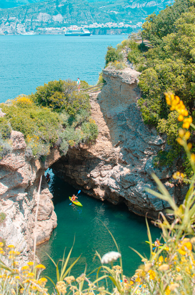 The view of Bagni Regina Giovanna near Sorrento from above, with a yellow kayak entering the lagoon.