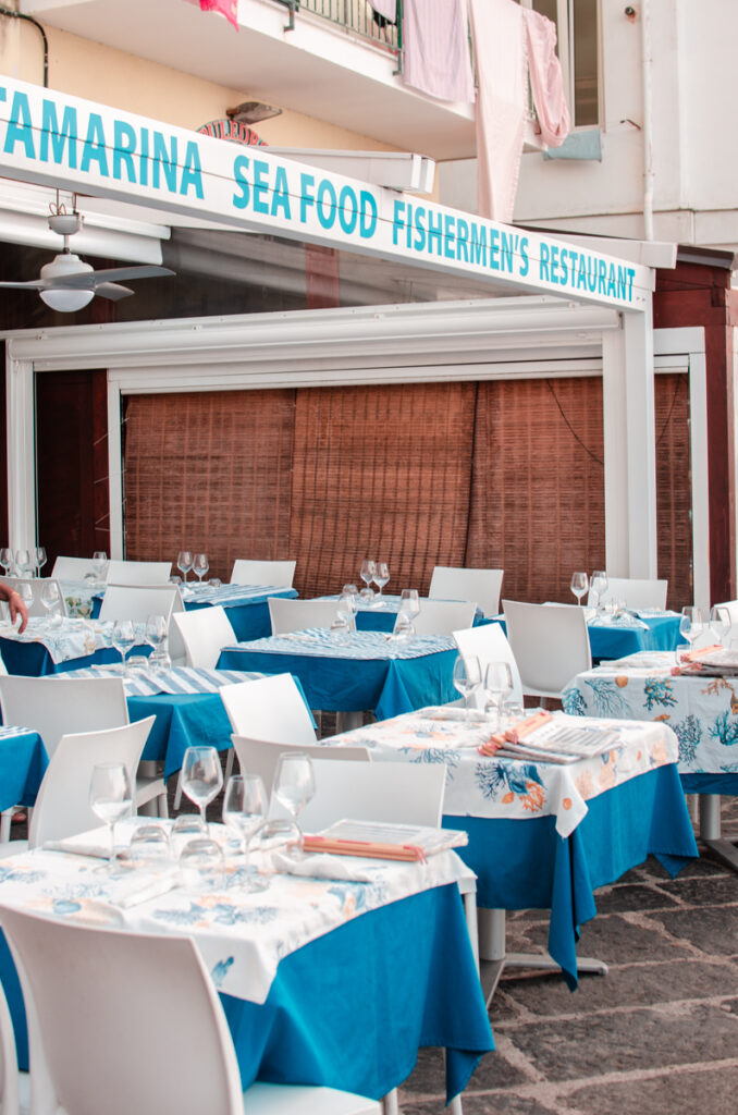 Tables at the Porta Marina Seafood Restaurant. Elegant tables all set for dining, with blue and white tablecloths and wine glasses.