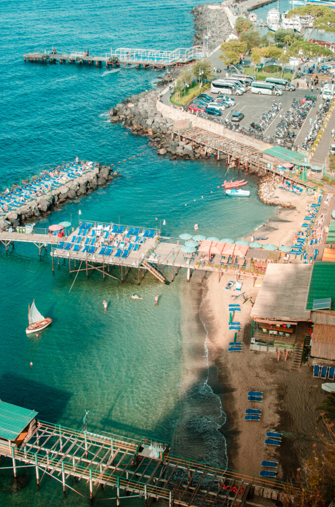 Seaside of Sorrento at Marina Piccola. Wooden decks built over the crystal-clear sea, filled with sun chairs.