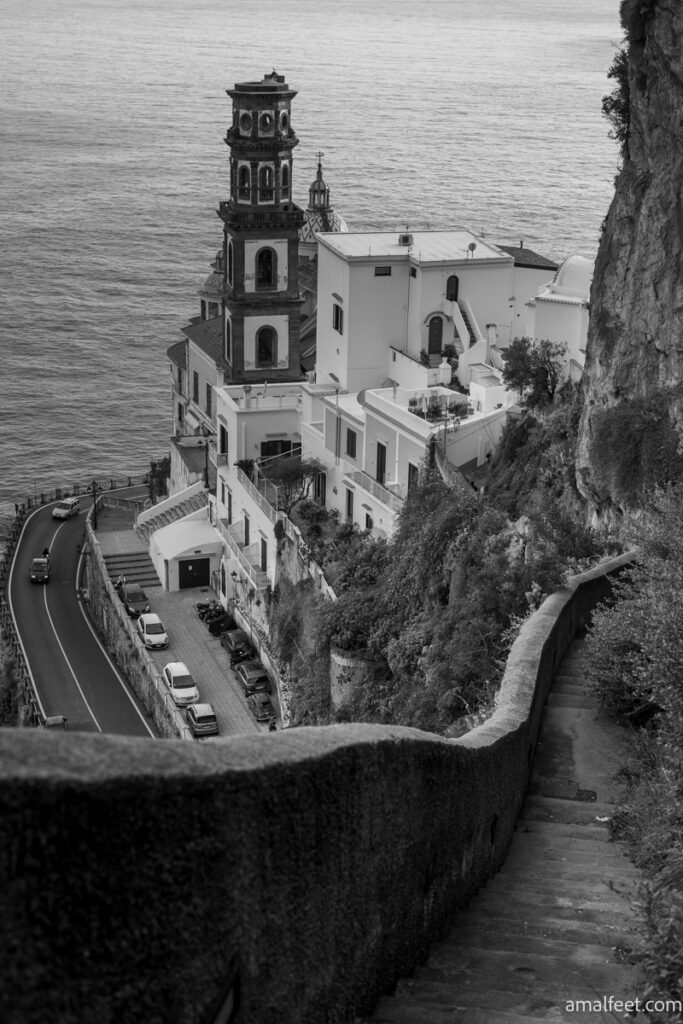 The view of Atrani. Steps leading down to the village. The bell tower dominates the scene. The see behind. Image edited to black and white, to match the vibes of the recent Netflix series filmed here "Ripley".