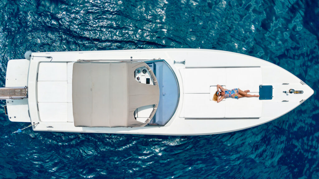 Aerial view of the company's boat. A woman is lounging on the comfortable mattress at the front (bow) of the yacht.