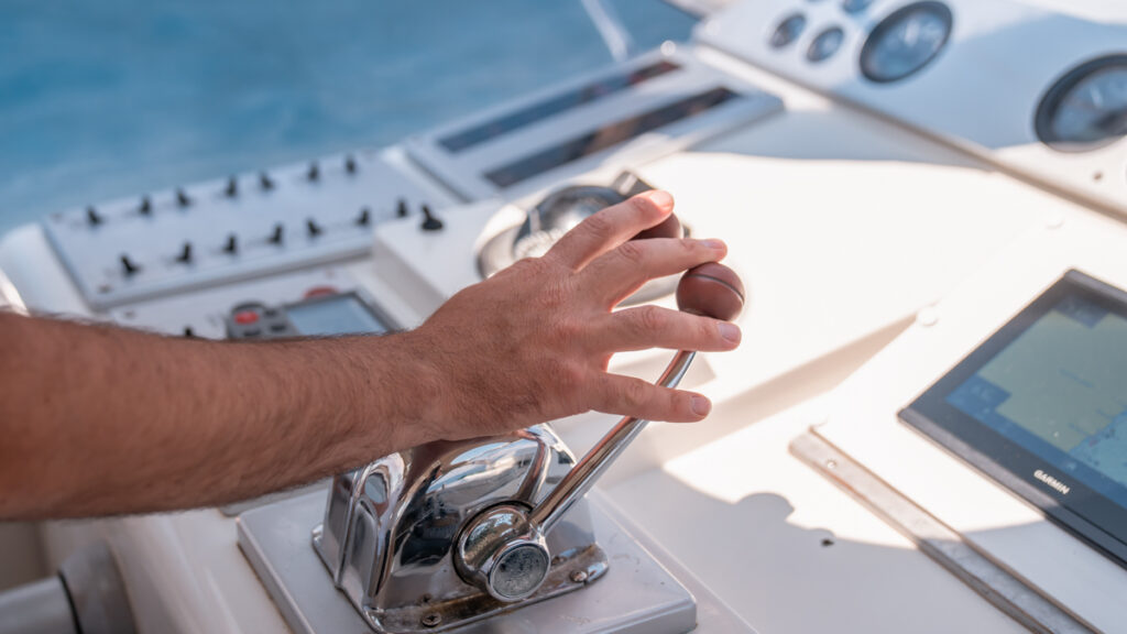 Close up on hand operating the throttle control on the boat to adjust the engine speed.