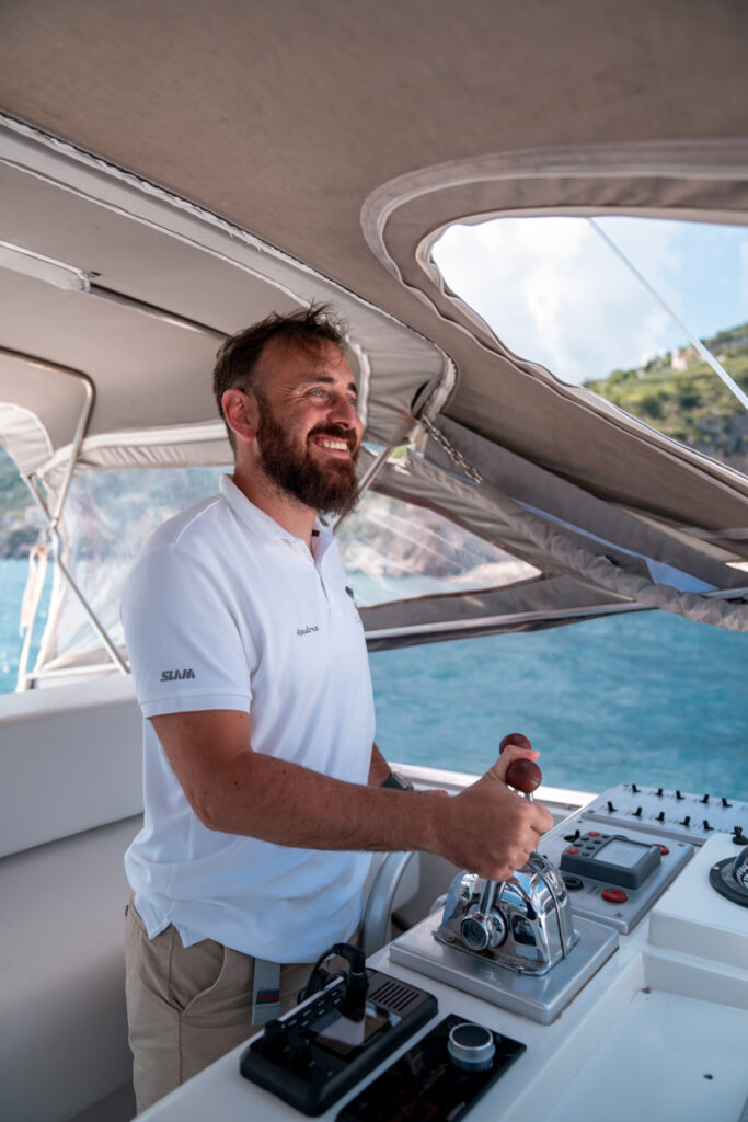 Captain Andrea of Il Canto del Mare smiling while operating his boat for private Amalfi Coast tours.