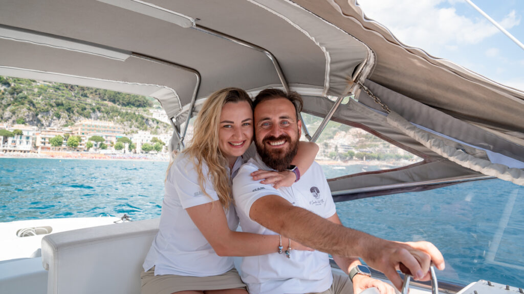 Captain Andrea and his fiancée, the crew of Il Canto del Mare Charter, smiling at the camera on their boat.